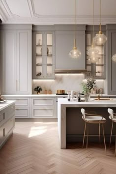 a kitchen with white cabinets and wooden floors, two bar stools at the island