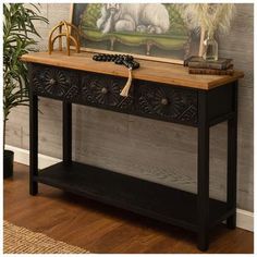 a wooden table with two drawers and a painting on the wall