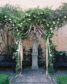 an outdoor wedding ceremony with flowers and greenery on the arch, in front of a building