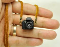 a person holding a camera necklace in their hand