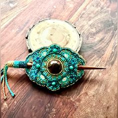 a beaded object sitting on top of a wooden table next to a piece of wood