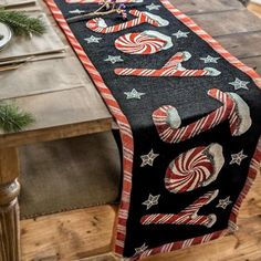 the table runner is decorated with candy canes and stars on black fabric, along with other holiday decorations