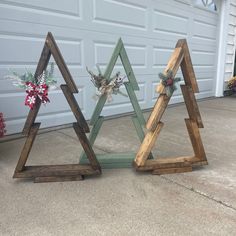 three wooden christmas trees sitting in front of a garage