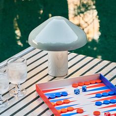 an outdoor game set up on a table next to wine glasses and a mushroom lamp