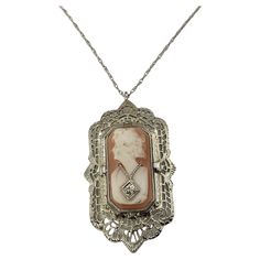 Vintage 12 Karat White Gold and Diamond Reversible Cameo Pendant- This stunning reversible 12K white gold filigree pendant pictures a lovely lady in profile decorated with one round single cut diamond on one side. The reverse side features elegant black onyx accented with one round single cut diamond. Suspends from a classic cable necklace. Approximate total diamond weight: .02 ct. Diamond clarity: VS2 Diamond color: H Size: 34 mm x 20 mm (pendant) 18 inches (necklace) Weight: 3.9 dwt. / 6.1 gr. Elegant White Gold Necklace With Locket, Elegant White Gold Locket Necklace, Elegant White Gold Locket Necklaces, Formal Filigree Medallion Jewelry, Antique White Gold Filigree Necklace, Antique White Gold Necklace With Filigree, Silver Oval Intaglio Necklace, Elegant Round Pendant Intaglio Necklace, Elegant Cameo Round Pendant Jewelry