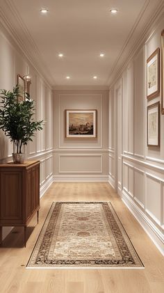 a long hallway with white walls and wood floors, framed pictures on the wall and a rug