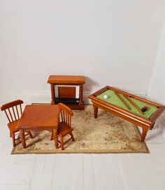 a miniature pool table and chairs are on the floor next to a small wooden table