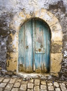 an old blue door is open on the side of a stone building with cobblestone flooring