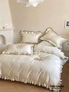 a bed with white sheets and pillows on top of it in front of a fireplace