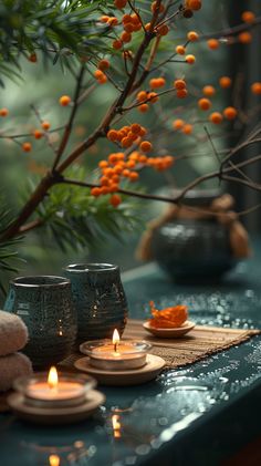 candles are sitting on a table with oranges in front of them and some branches