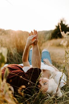 a woman laying in the grass with her hand up