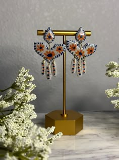 an image of earrings on a stand with flowers in the foreground and white background