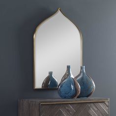 two vases and a mirror on a dresser in a room with grey walls,