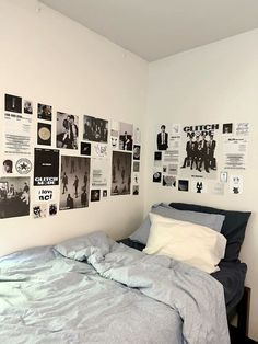 an unmade bed in a small room with posters on the wall