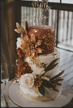 a three tiered cake decorated with flowers and feathers