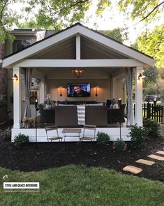 an outdoor living area with chairs and a television on the wall in front of it