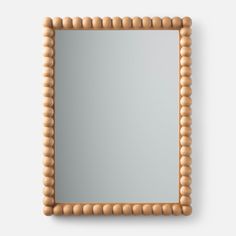 a wooden frame mirror with beaded edges on a white wall, viewed from above