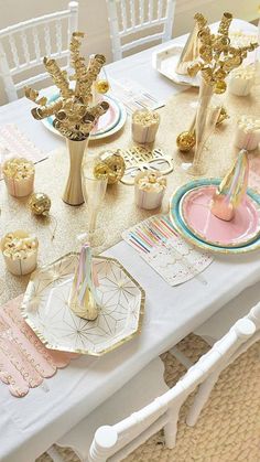 the table is set with gold and pink decorations