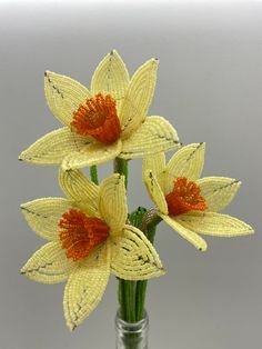 three yellow flowers are in a glass vase