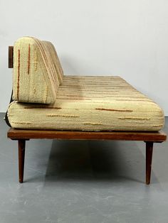 a couch that is sitting on top of a wooden frame with a striped fabric covering it