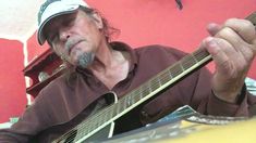 a man is playing an acoustic guitar in front of a red wall