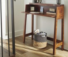 a wooden table with a basket underneath it and a clock on the wall next to it