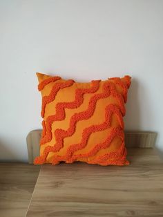 an orange pillow sitting on top of a wooden table