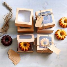 four boxes with different types of pastries in them on a table next to tags and twine