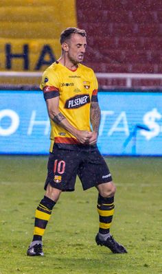 a man standing on top of a field next to a soccer ball in the rain