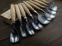 six spoons are lined up on a wooden table