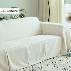 a white couch sitting on top of a rug next to a window