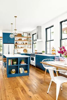 an open kitchen and dining room with blue cabinets, wood flooring and white walls