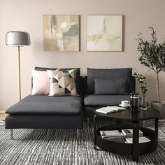 a living room with grey couches and pillows on top of the sofa, next to a coffee table