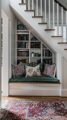 a living room with bookshelves and a couch under the stair case in front of it