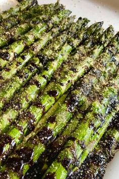 grilled asparagus on a white plate with brown sauce and seasoning sprinkles