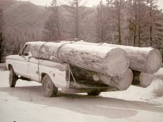 a white truck carrying a large log on the back of it's bed