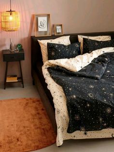 a bed with black and white stars on it in a room next to a lamp