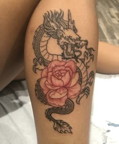 a woman's thigh with a rose and dragon tattoo on it