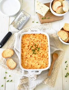 a casserole dish with cheese and bread on the side