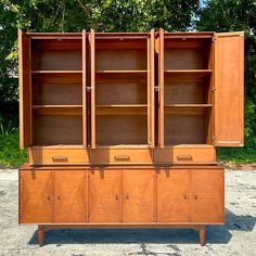 an old wooden cabinet with two doors and three drawers on the front, sitting in gravel