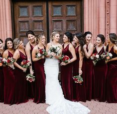 a group of women standing next to each other in front of a door holding bouquets