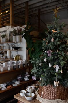 a small christmas tree in a wicker basket with ornaments hanging from it's sides