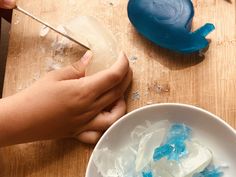 a person is making something blue and white in a bowl with ice cubes on the table