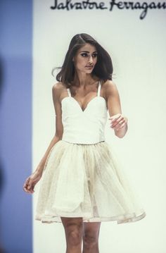 a woman is walking down the runway wearing a white dress