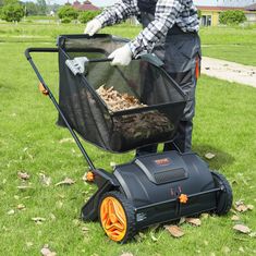 a man is pushing a lawn mower with trash in it on the grass outside