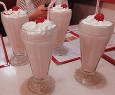 there are three drinks on the table with whipped cream in them and one has a straw