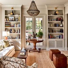 a living room filled with furniture and bookshelves next to a window covered in windows