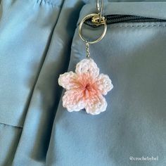 a crocheted flower keychain hanging from a blue jacket with a metal ring