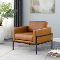 a brown leather chair sitting on top of a white floor next to a plant in a living room