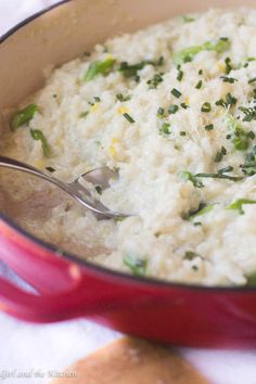 a red pot filled with rice and broccoli on top of a white table